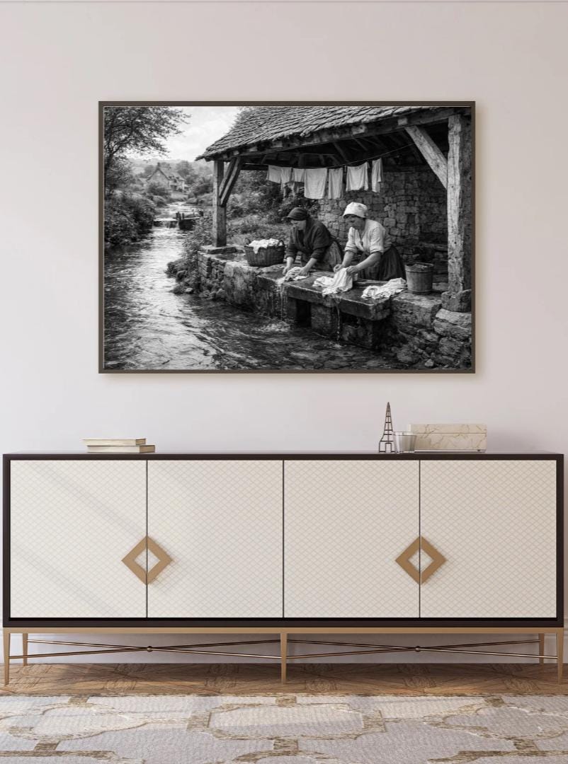 Peut inclure: Tirage encadré en noir et blanc représentant deux femmes lavant du linge dans un ruisseau. La scène se déroule dans un environnement rural rustique avec une structure en pierre et du linge suspendu. L'image évoque l'histoire et la vie traditionnelle.